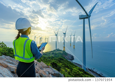 Technician in Neon Green Vest Inspecting Wind Farm Turbines by the Ocean 137071954