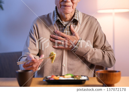 一位老年男子正在吃午飯,突然胃部不適,伸手去拿東西 一位老年男子正在吃午飯,突然胃部不適,伸手去拿東西 137072178