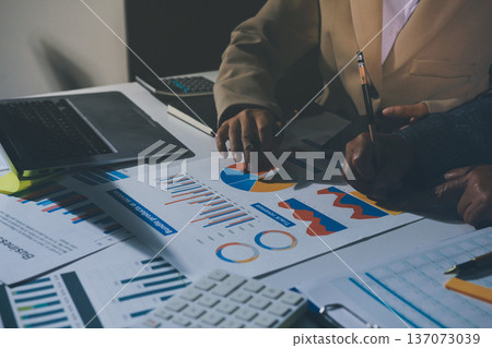 business documents on office table with tablet, smart phone and laptop and two colleagues discussing data business documents on office table with tablet, smart phone and laptop and two colleagues discussing data 137073039