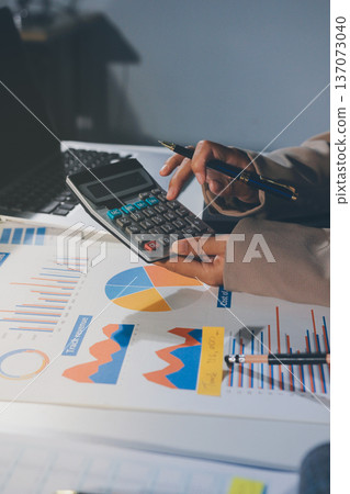 business documents on office table with tablet, smart phone and laptop and two colleagues discussing data business documents on office table with tablet, smart phone and laptop and two colleagues discussing data 137073040