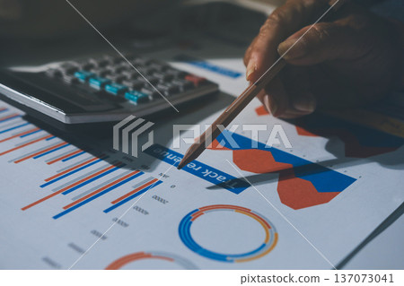 business documents on office table with tablet, smart phone and laptop and two colleagues discussing data business documents on office table with tablet, smart phone and laptop and two colleagues discussing data 137073041