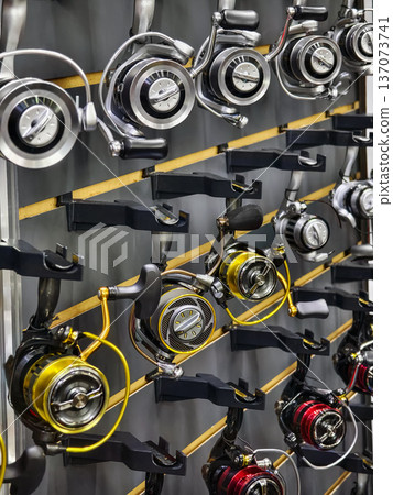 Fishing reels on display in a shop showing various brands during a busy shopping day Fishing reels on display in a shop showing various brands during a busy shopping day 137073741