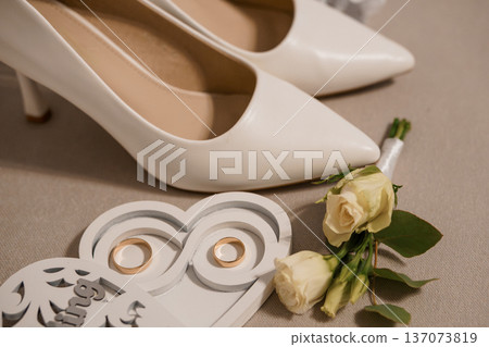 White Wedding Heels with Gold Rings and Rose Bouquet on Neutral Background in Minimalist Style White Wedding Heels with Gold Rings and Rose Bouquet on Neutral Background in Minimalist Style 137073819