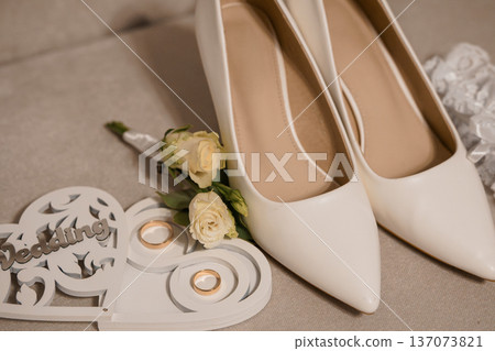 White Wedding Shoes with Rings and Rose Bouquet on Soft Textured Background for Romantic and Elegant Wedding Theme White Wedding Shoes with Rings and Rose Bouquet on Soft Textured Background for Romantic and Elegant Wedding Theme 137073821