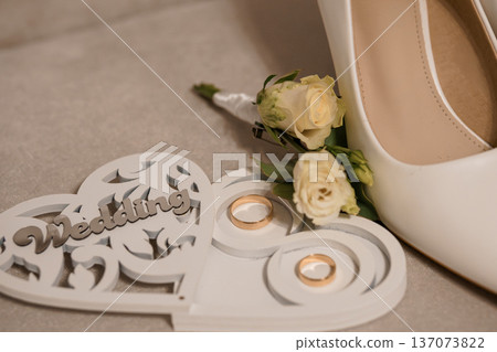 Elegant White Wedding Shoe with Rose Bouquet and Gold Rings on Heart-Shaped Display Stand 137073822
