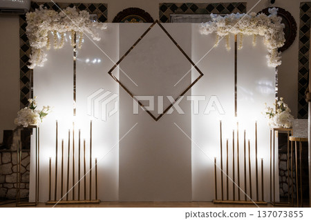 Elegant White Floral Arch with Gold Geometric Accents and Candlelight for Wedding Ceremony or Event Backdrop 137073855