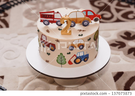 Colorful Car-Themed Birthday Cake with Number 2 Candle and Toy Vehicles on White Fondant Surface Colorful Car-Themed Birthday Cake with Number 2 Candle and Toy Vehicles on White Fondant Surface 137073873