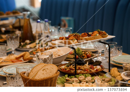 Elegant Buffet Spread with Fresh Appetizers, Bread, and Beverages on a Stylish Table Setting 137073894