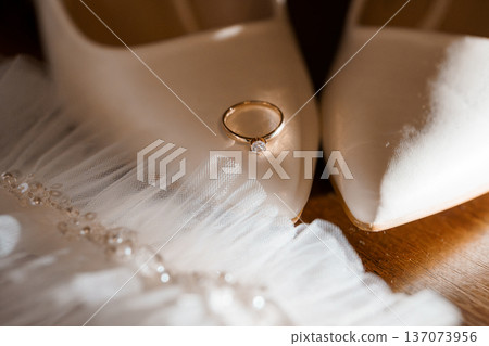 Elegant Wedding Ring with Diamond on White High Heels and Tulle Dress Fabric Background 137073956