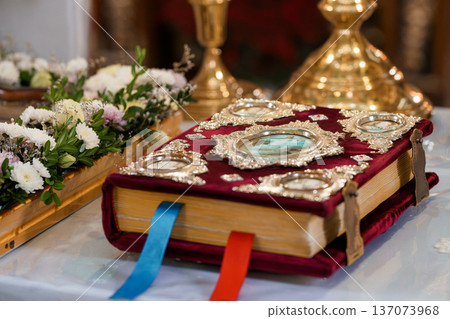 Ornate Religious Book with Silver Embellishments and Floral Arrangements on Church Altar in Warm Golden Light Ornate Religious Book with Silver Embellishments and Floral Arrangements on Church Altar in Warm Golden Light 137073968