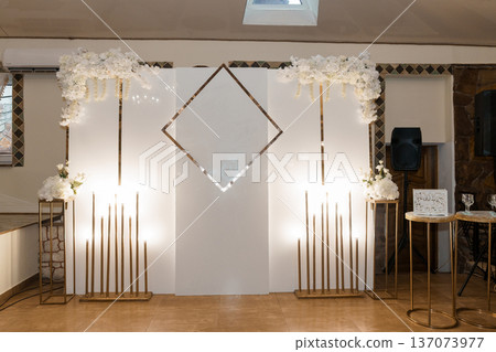 Elegant White Floral Arch with Gold Geometric Accents for Wedding Ceremony or Event Backdrop Design Elegant White Floral Arch with Gold Geometric Accents for Wedding Ceremony or Event Backdrop Design 137073977