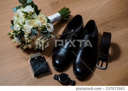 Elegant Wedding Bouquet with Black Dress Shoes, Belt, Watch, and Perfume on Wooden Floor Elegant Wedding Bouquet with Black Dress Shoes, Belt, Watch, and Perfume on Wooden Floor 137073981
