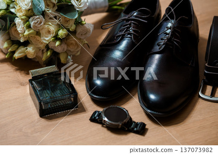 Elegant Black Dress Shoes Beside Wedding Bouquet and Accessories on Wooden Surface Elegant Black Dress Shoes Beside Wedding Bouquet and Accessories on Wooden Surface 137073982