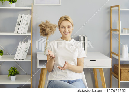 Woman sitting at desk in bright modern room smiling friendly communication or teaching from home Woman sitting at desk in bright modern room smiling friendly communication or teaching from home 137074262