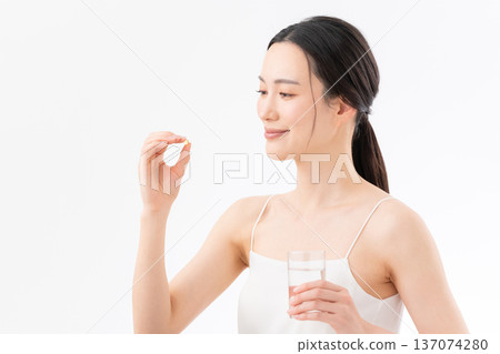 白色背景下，一位女性正在服用保健品的健康圖片 137074280