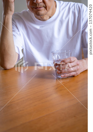 一位老年男子手捧酒杯,雙手抱頭 一位老年男子手捧酒杯,雙手抱頭 137074420