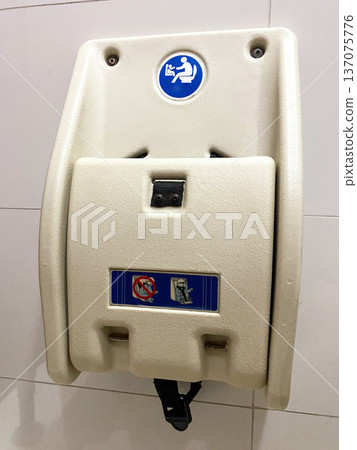 Wall-mounted baby changing station with safety strap and signage for proper usage in a public restroom setting 137075776