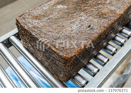 The close up image of the jagged brown natural raw rubber bales surface, lumpy solid block standard Thai rubber, in a factory. 137076371