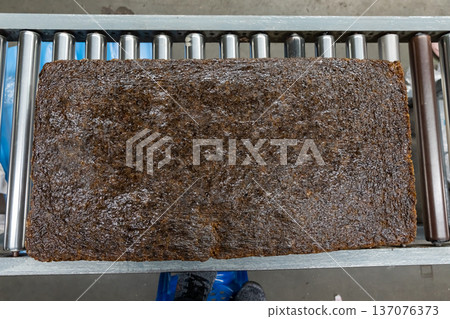 The natural rubber bales products on the industrial automatic conveyor belt machine in a rubber factory. 137076373