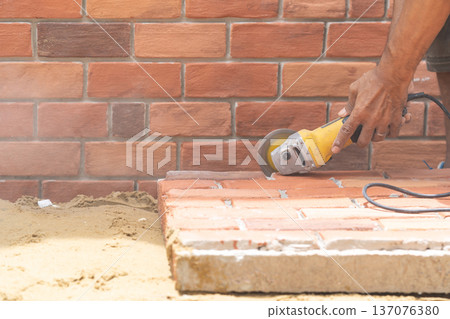 Close up worker holds Hand-Hold Sawing Machine and cuts brick foam plate board for wall installation. 137076380