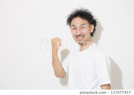 一位中年蓄須男子身穿襯衫，揮舞著拳頭，微笑著看著鏡頭。 137077457