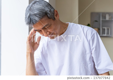 一位老人在窗邊摀著頭。 137077842