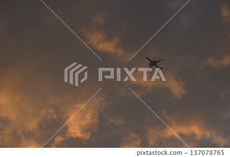 plane flying throgh white and orange cloud floating on sky in twilight sunset sky at evening plane flying throgh white and orange cloud floating on sky in twilight sunset sky at evening 137078765