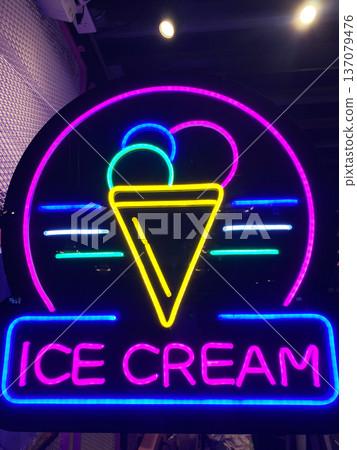 Neon sign featuring colorful ice cream cone design with the words Ice Cream illuminated in bright lights against a dark background in a modern setting Neon sign featuring colorful ice cream cone design with the words Ice Cream illuminated in bright lights against a dark background in a modern setting 137079476