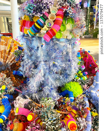 Decorative arrangement made from used plastic bottle caps and colorful materials, showcasing creativity in recycling, displayed in a vibrant indoor setting Decorative arrangement made from used plastic bottle caps and colorful materials, showcasing creativity in recycling, displayed in a vibrant indoor setting 137079477