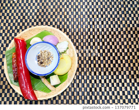 Assorted spices and fresh ingredients for preparing Thai cuisine arranged on a woven bamboo mat, showcasing vibrant colors and textures in a circular bamboo plate Assorted spices and fresh ingredients for preparing Thai cuisine arranged on a woven bamboo mat, showcasing vibrant colors and textures in a circular bamboo plate 137079771