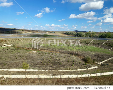 Scenic view of Turkey's countryside from a bus window, showcasing rolling hills, sparse vegetation, and a clear blue sky with scattered clouds Scenic view of Turkey's countryside from a bus window, showcasing rolling hills, sparse vegetation, and a clear blue sky with scattered clouds 137080163