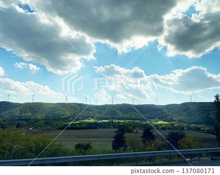 Scenic view of rolling green hills and wind turbines under a partly cloudy sky captured from a bus window while traveling through Turkey's countryside Scenic view of rolling green hills and wind turbines under a partly cloudy sky captured from a bus window while traveling through Turkey's countryside 137080171