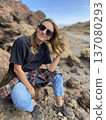 Woman Outdoor Smile. Relaxed Female Traveler Posing Amid Rugged Desert Terrain With Joyful 137080293