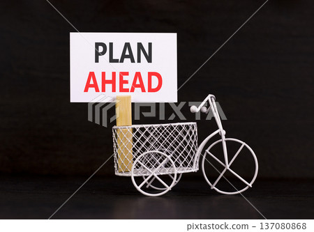 Plan ahead symbol. Concept word Plan ahead on beautiful white paper. Beautiful wooden clothespin. Miniature white bicycle. Beautiful black background. Business plan ahead concept. Copy space. 137080868