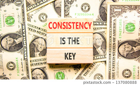 Consistency is the key symbol. Concept words Consistency is the key on beautiful wooden blocks. Beautiful dollar bills background. Dollar bills. Business consistency is the key concept. Copy space. 137080888