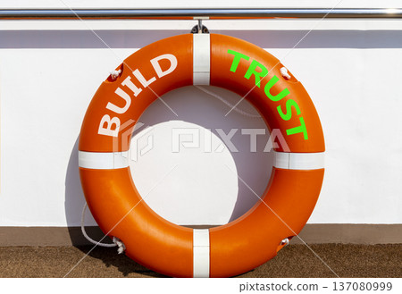 Build trust symbol. Concept words Build trust on beautiful orange lifebuoy. Beautiful white ship's board background. Business and build trust concept, copy space. Build trust symbol. Concept words Build trust on beautiful orange lifebuoy. Beautiful white ship's board background. Business and build trust concept, copy space. 137080999