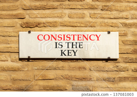 Consistency is the key symbol. Concept words Consistency is the key on beautiful white marble sign plate. Beautiful brick wall background. Business consistency is the key concept. Copy space. 137081003