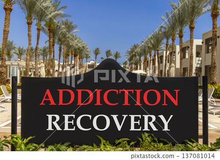 Addiction recovery symbol. Concept words Addiction recovery on beautiful big black road sign. Beautiful blue sky palm trees background. Psychology addiction recovery concept. Copy space. 137081014