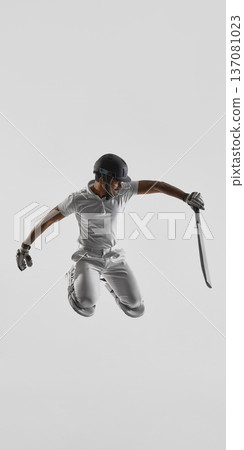 Cricket player jumping with bat extended sideways on white studio background in full cricket gear Cricket player jumping with bat extended sideways on white studio background in full cricket gear 137081023