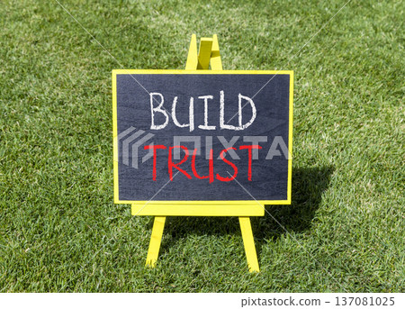 Build trust symbol. Concept words Build trust on beautiful black blackboard. Beautiful green grass lawn background. Business and build trust concept, copy space. Build trust symbol. Concept words Build trust on beautiful black blackboard. Beautiful green grass lawn background. Business and build trust concept, copy space. 137081025