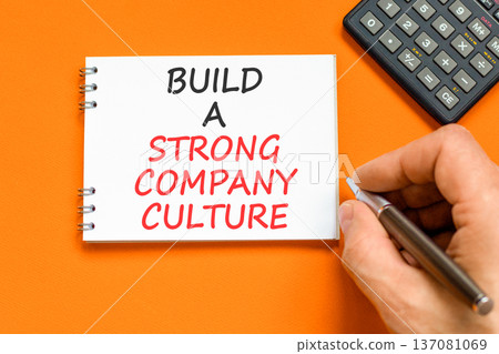Strong company culture symbol. Concept words Build a strong company culture on beautiful white note. Beautiful orange background. Business strong company culture concept. Copy space. 137081069