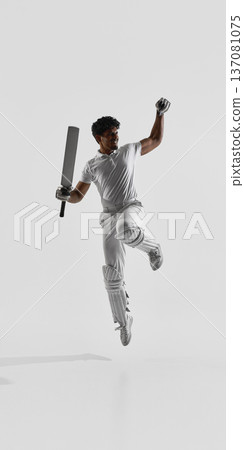 Cricket player jumping holding bat and clenched fist on white studio background in full protective gear. Cricket player jumping holding bat and clenched fist on white studio background in full protective gear. 137081075