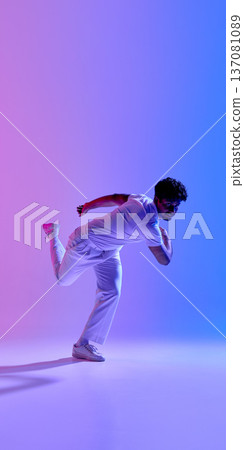 Male cricket bowler in dynamic motion under neon gradient light. Male cricket bowler in dynamic motion under neon gradient light. 137081089
