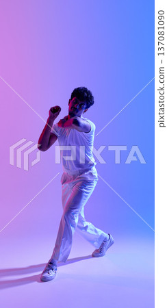 Young male cricket player in bowling action pose under neon gradient light Young male cricket player in bowling action pose under neon gradient light 137081090