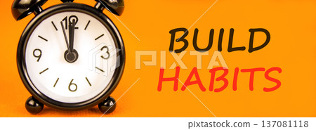 Build habits symbol. Concept word Build habits on beautiful orange paper. Beautiful black alarm clock. Beautiful orange paper background. Business build habits concept. Copy space. Build habits symbol. Concept word Build habits on beautiful orange paper. Beautiful black alarm clock. Beautiful orange paper background. Business build habits concept. Copy space. 137081118