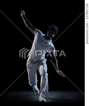 Cricket player dynamic pose with raised arm and ball on dark studio background. Concept of athlete branding, social media sports content, commercial photo for activewear label and online promotion. Cricket player dynamic pose with raised arm and ball on dark studio background. Concept of athlete branding, social media sports content, commercial photo for activewear label and online promotion. 137081156