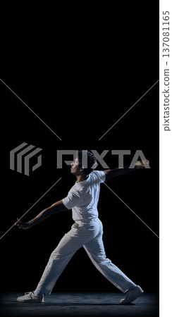 Cricket bowler in dramatic pose on dark background wearing white uniform mid delivery motion. Cricket bowler in dramatic pose on dark background wearing white uniform mid delivery motion. 137081165