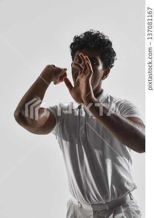Cricket bowler preparing to deliver ball isolated on white studio background. Cricket bowler preparing to deliver ball isolated on white studio background. 137081167