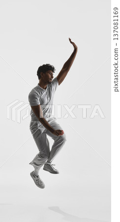Cricket player jumping while bowling with raised arm on white studio background. Cricket player jumping while bowling with raised arm on white studio background. 137081169