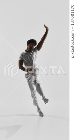 Cricket player bowling with ball in dynamic pose on white studio background. Cricket player bowling with ball in dynamic pose on white studio background. 137081170